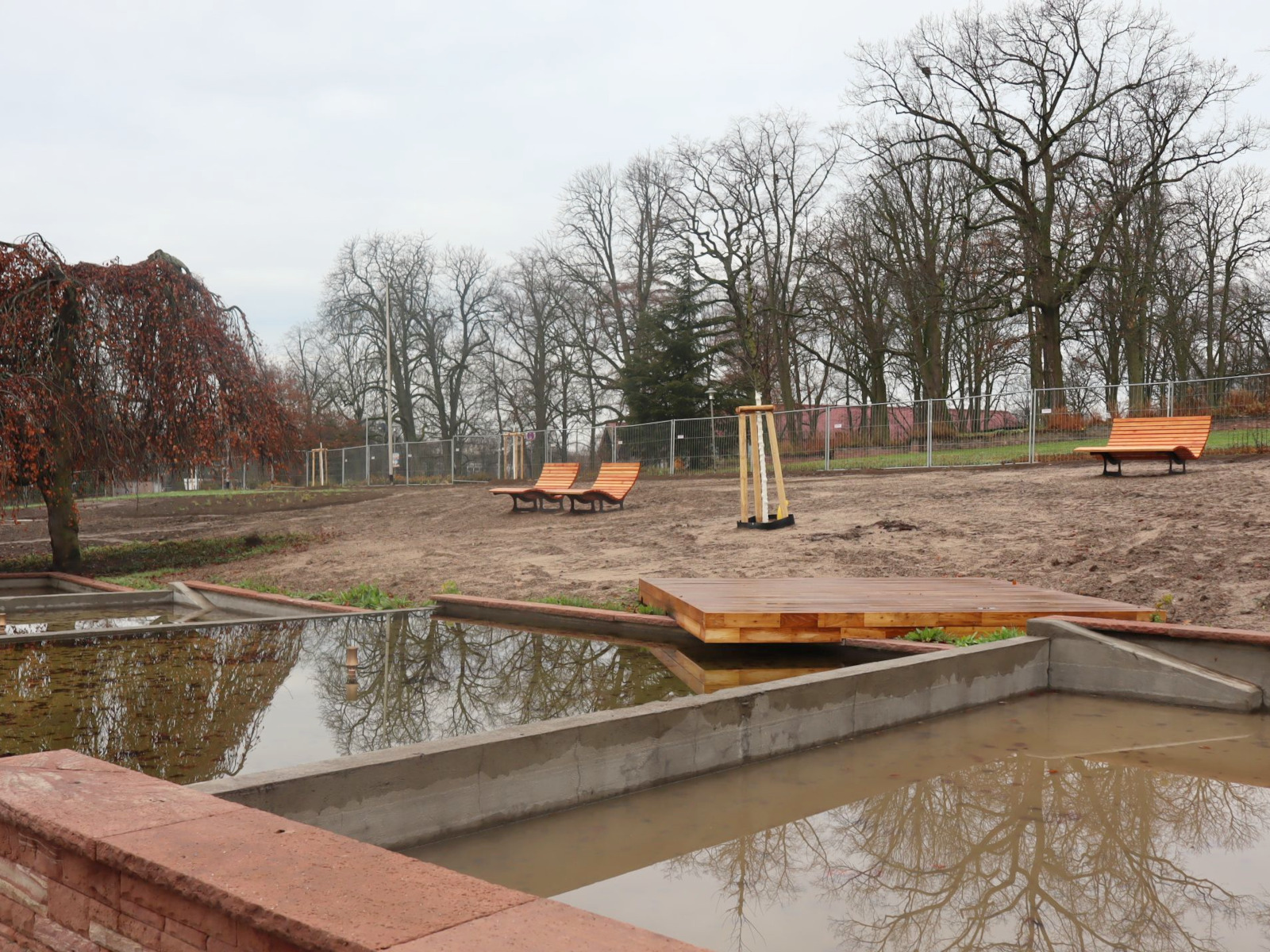 Wasserbecken und künftige Wiese mit Liegebänken.