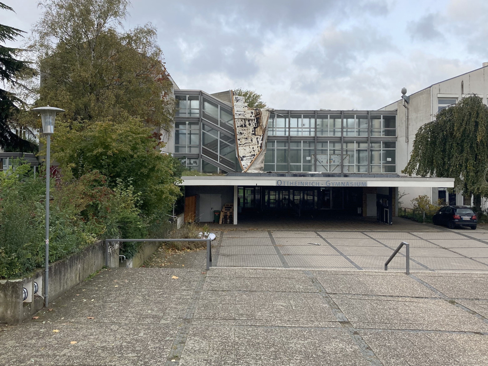 Haupteingang des Gebäudes mit durch einen Sturm zerstörter Dachabdeckung.