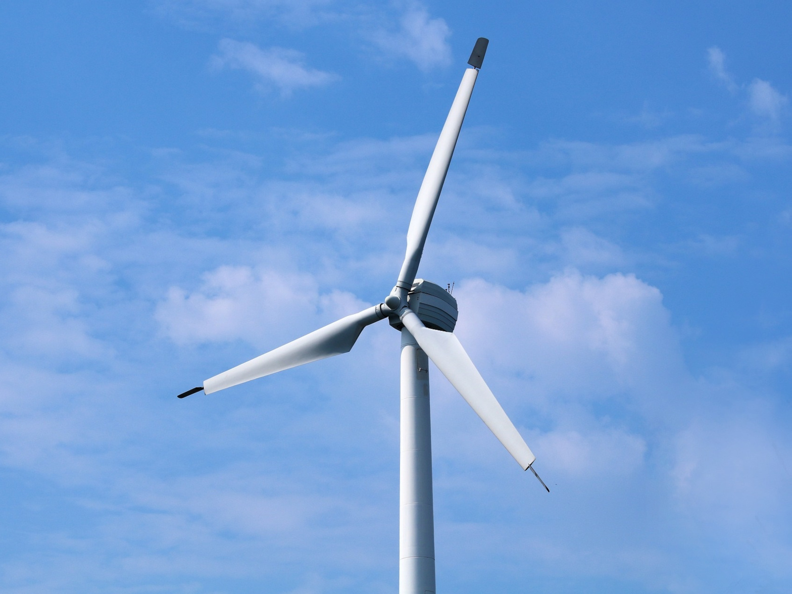 Windturbine vor blauem Himmel.