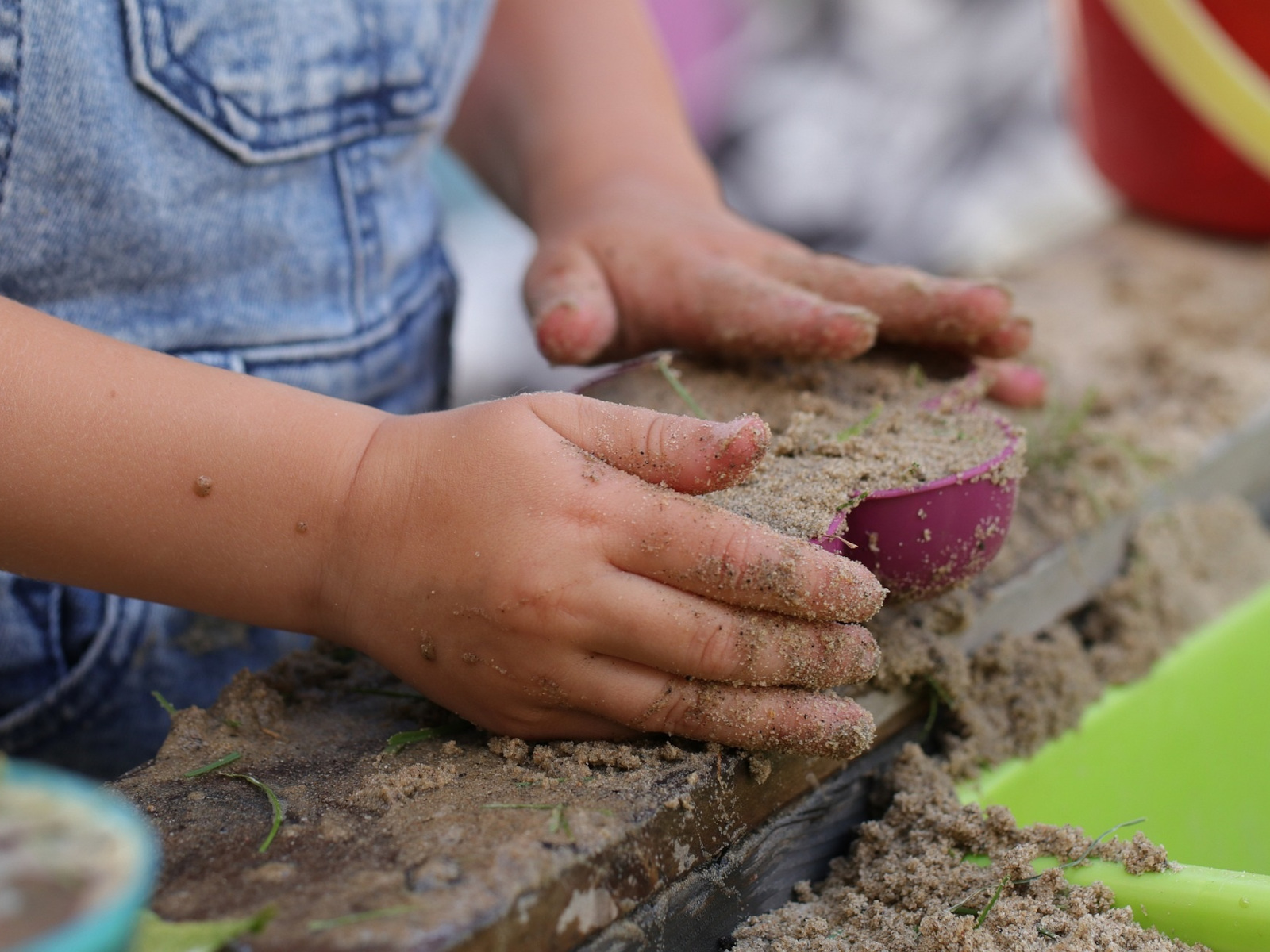 Kinderhände spielen im Sandkasten.